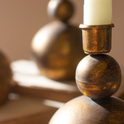 Set of 3 graduated antique brass stacked sphere taper candle holders styled on a wood tray in a bright living room — The Red Hound Gifts