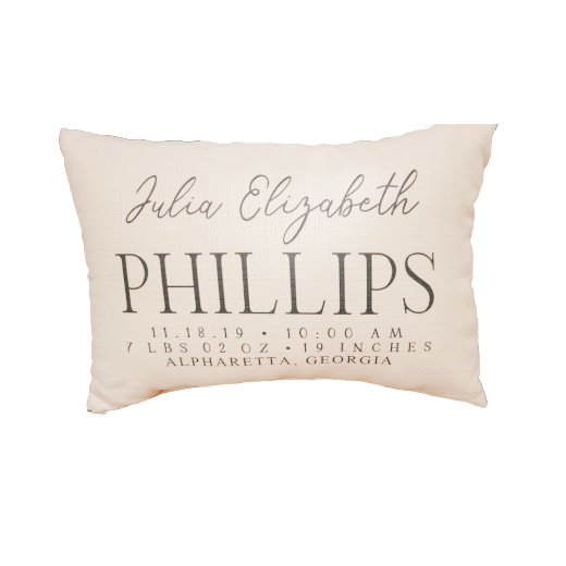 Personalized pillow with baby details on a beige chair