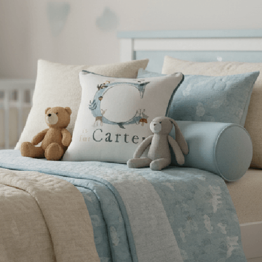 Children's bedroom featuring a pillow that has "C for Carter" on a bed.
