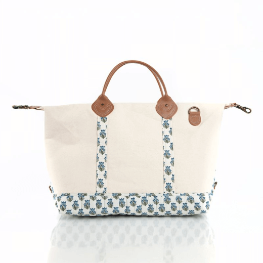 Canvas bag with blue floral pattern and brown leather handles on a white background
