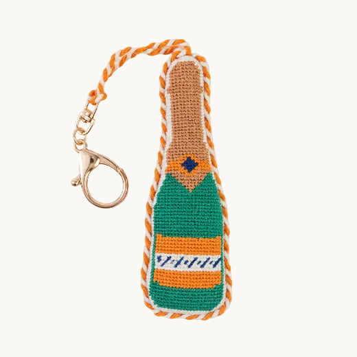 Needlepoint champagne bottle bag charm in green and orange with orange and white rope trim and a gold tone clasp