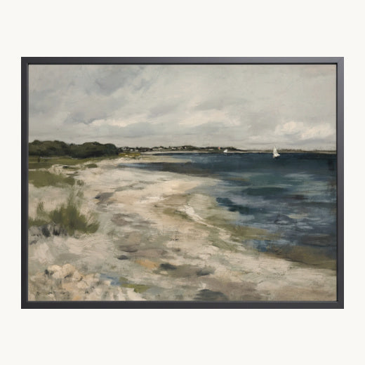 A framed landscape painting depicting a sandy beach meeting the blue water of the sea, with a cloudy sky and a small sailboat on the horizon, presented in a black frame.