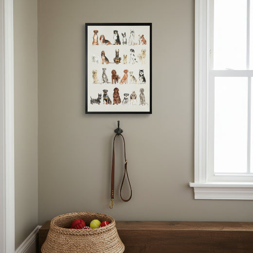 A framed art print featuring a watercolor-style illustration of multiple dog breeds arranged in rows on an off-white background, shown against a light neutral backdrop.