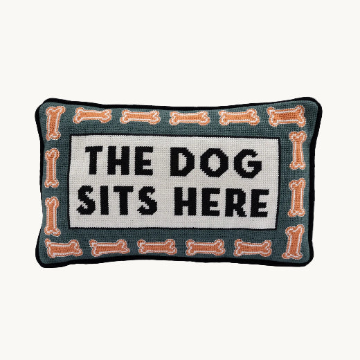 Dog Sits Here needlepoint pillow styled on a brown leather wingback chair