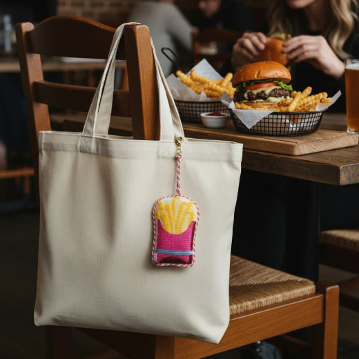 Needlepoint french fries bag charm in bright pink and yellow with pink and white rope trim and gold tone clasp