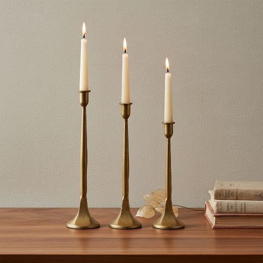 Set of 3 graduated gold cast iron taper candle holders on a cream background — The Red Hound Gifts