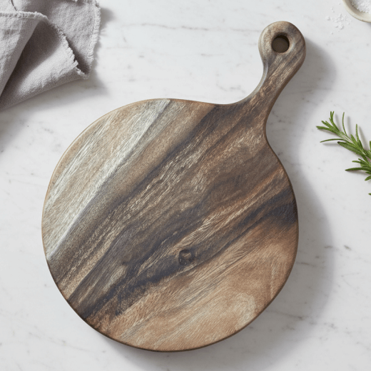 Wooden charcuterie tray on a marble surface with a kitchen towel and rosemary in the background
