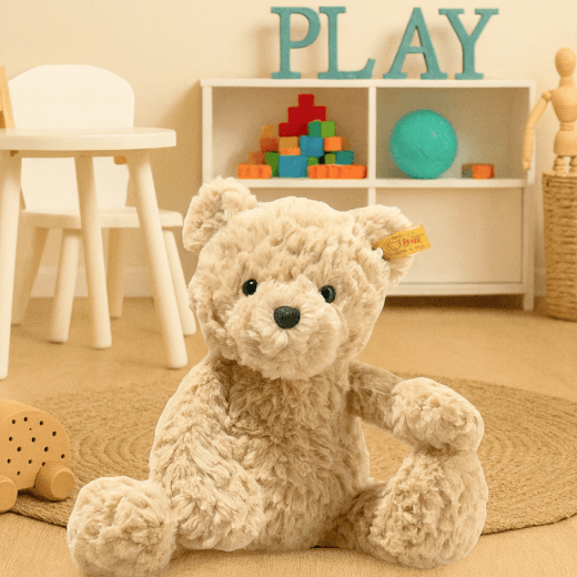 Plush teddy bear in a playroom with toys and 'PLAY' sign