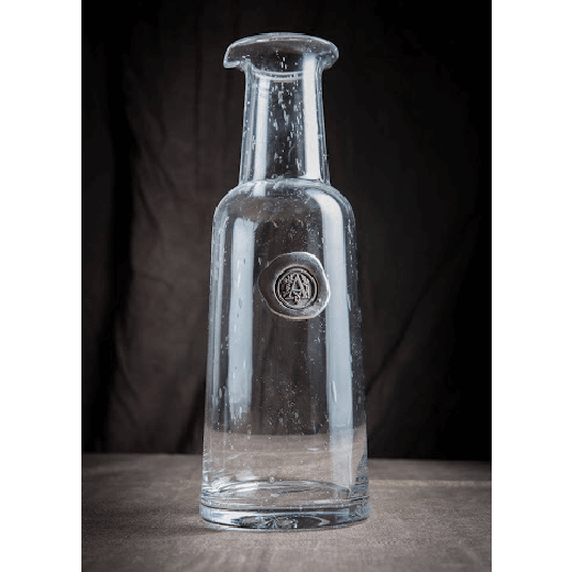 Clear decanter bottle with a pewter intital emblem on the front
