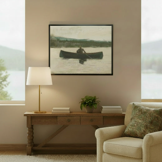 A framed painting depicting a person rowing in a dark canoe on a calm lake, with distant hills and a light sky. 