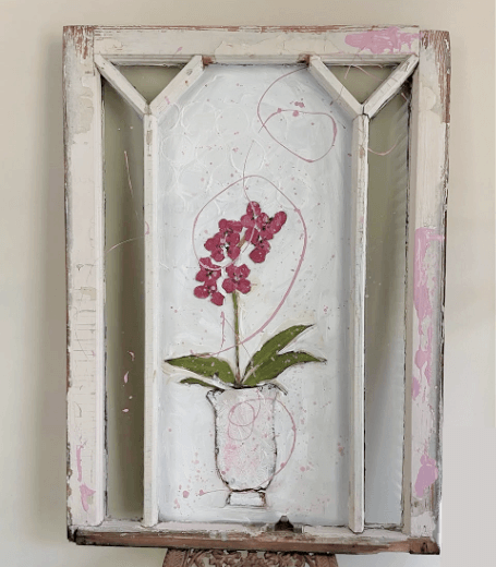 Decorative wall art with a magenta pink orchid in a vase on an old wood and glass window frame.