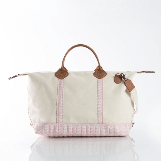 Cream canvas weekender bag with light pink patterned trim, leather handles, and coordinating leather accents against a white background