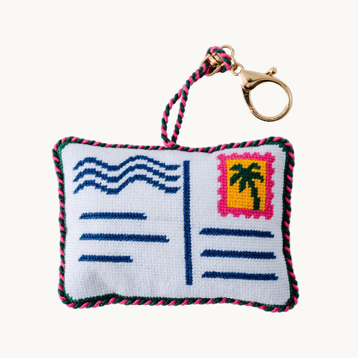 Needlepoint postcard bag charm with palm tree stamp detail, navy wave lines, and multicolor rope trim with gold tone lobster clasp