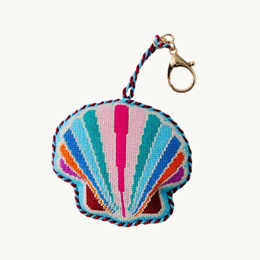 Needlepoint seashell bag charm in multicolor pink, teal, and blue with navy rope trim and gold tone clasp
