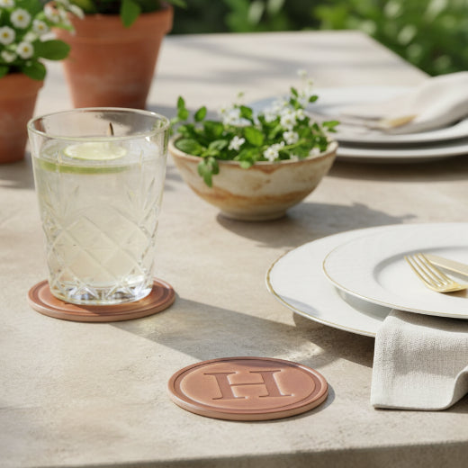 A round brown leather monogram coaster featuring an embossed 'H' in the center - The Red Hound Gifts