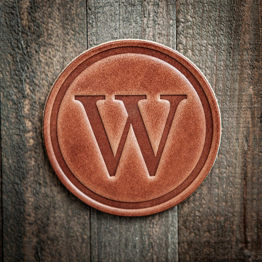 Signature leather initial coaster embossed with the letter W on a rustic wood surface — The Red Hound Gifts