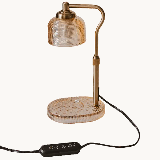 Decorative candle warmer lamp with neutral glass shade and gold lamp arm