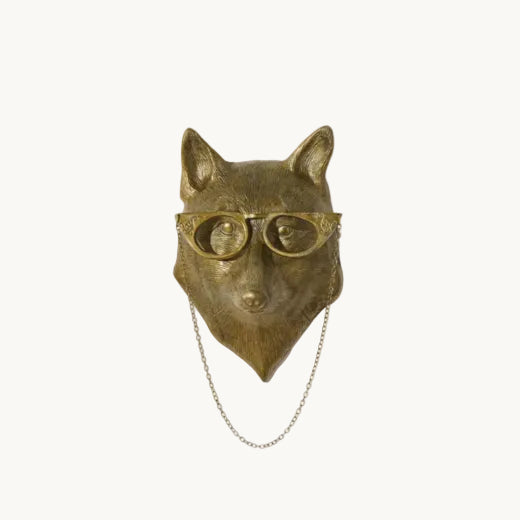 Antique brass finish fox wall mount wearing round spectacles with a draped chain on an off white background.