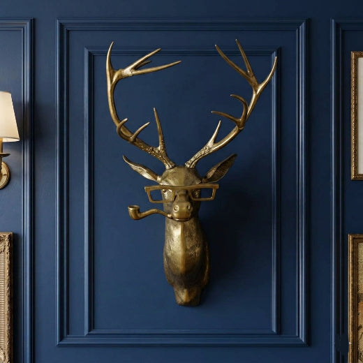 Antique brass finish buck head wall mount with antlers, squared spectacles, and a pipe.